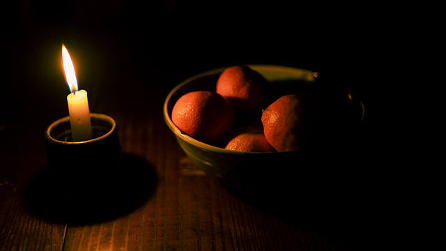CANDLE AND A BOWL FULL OF ORANGES