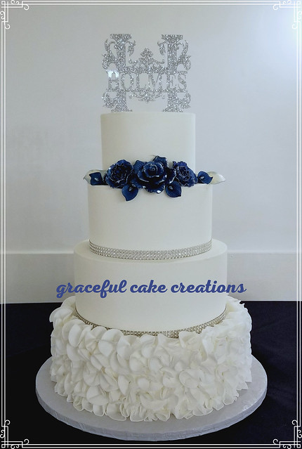 Elegant White Butter Cream Wedding Cake with Rhinestone Ribbon and Navy Blue Sugar Paste Roses