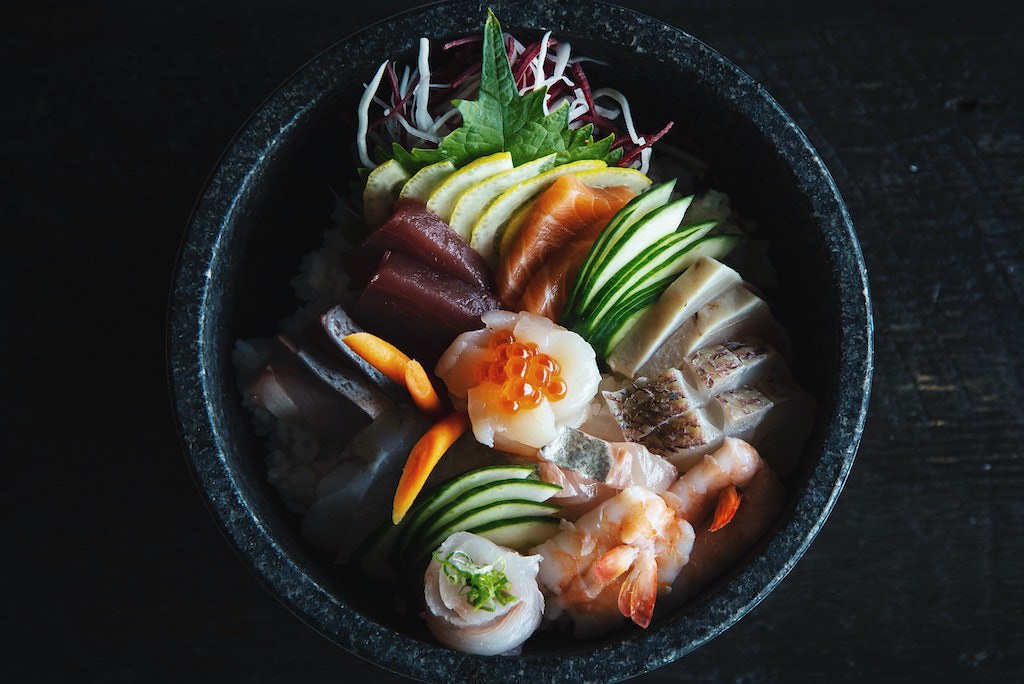 Kimbap vs sushi: An overhead shot of different types of raw fish over rice. This is a type of sushi. 