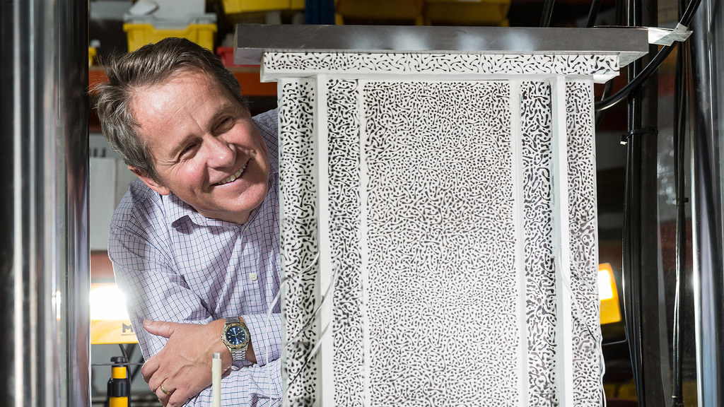 a smiling male academic leans next to a laminated skin panel used in composite wings for Airbus