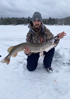 Photo of man holding a pike while fishing on frozen lake