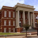 Forrest County Courthouse - Hattiesburg, MS This courthouse is on the National Register of historic places as part of the Hub City Historic District. Here is the text from the nominating form:

Forrest County Courthouse, 628, 630 Main Street. Neo-Classical Revival. Three-story brick with stone trim, nine-by-nineteen-bay, raised basement, main entrance at second floor. Two-story balconied portico supported by Ionic columns. Stone trim at lintels, string courses, pilaster bases and capitals, at cornice. Two-story eight-bay brick enlargement (628 Main Street), stone sills and lintels, added at southeast corner and set back from street creating small park-like area with trees and shrubs. 1905, remodeled 1922.


