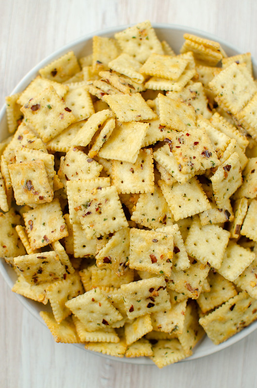 Overhead shot of mini Saltine crackers coated in ranch seasoning, spices, and herbs on a plate white