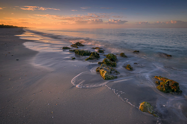 Morning sunlight strikes the rocks on the beach just after sunrise on Caspersen Beach near South Venice, Florida