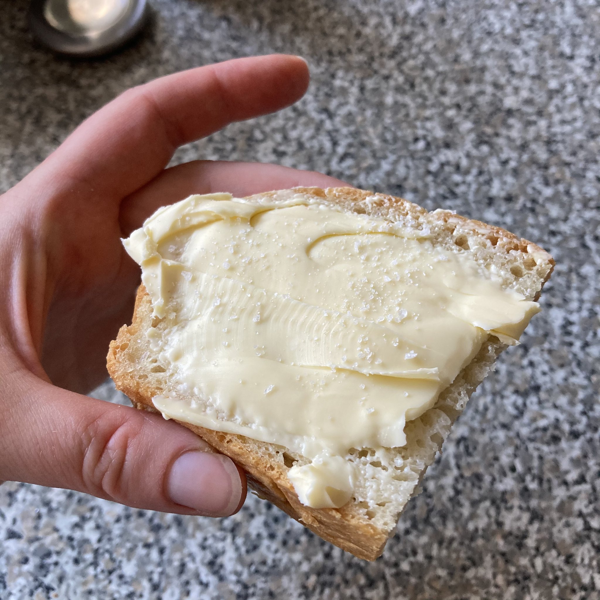 homemade white bread spread with butter and sprinkled with salt flakes