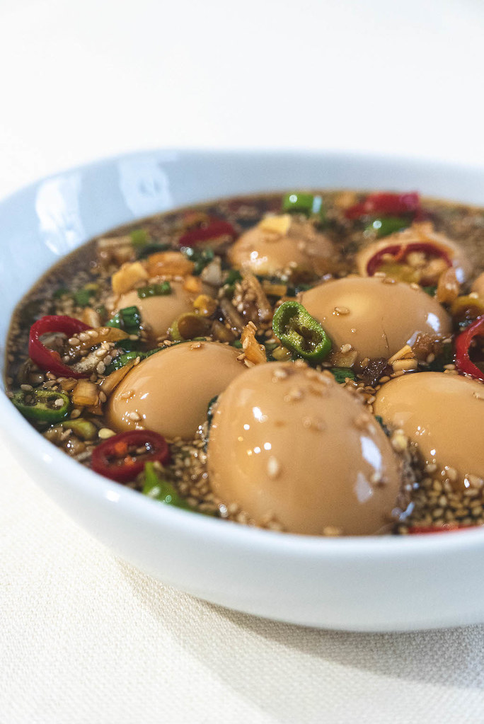 A Bowl of Korean marinated eggs (mayak eggs). The eggs sit in the marinade made of soy sauce and peppers. 