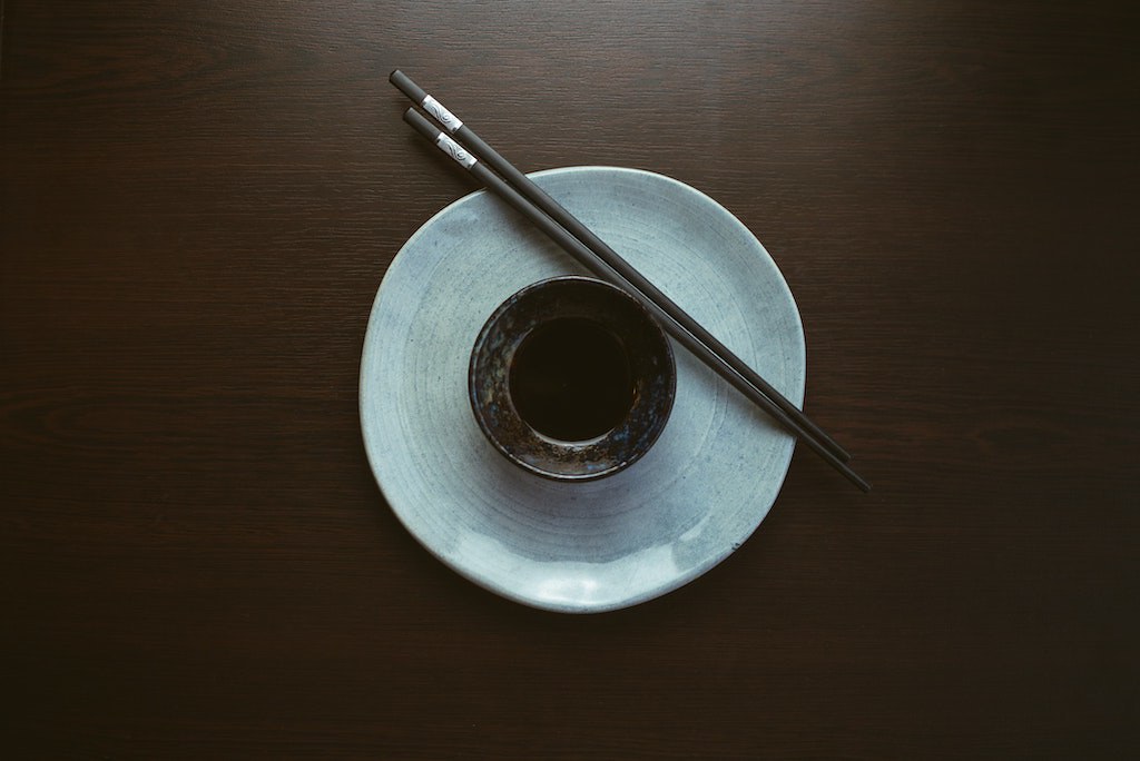 a bowl of tamari or soy sauce sitting on a dark surface. 