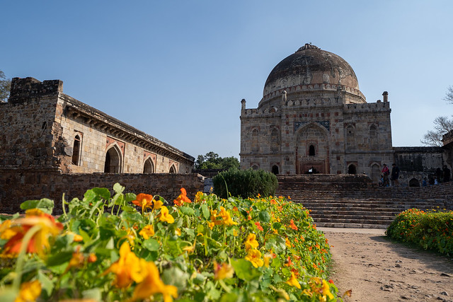 New Delhi, India - March 17, 2020: Ancient Bara Gumbad Tomb Lodi Gardens New Delhi India, with flowers in foreground