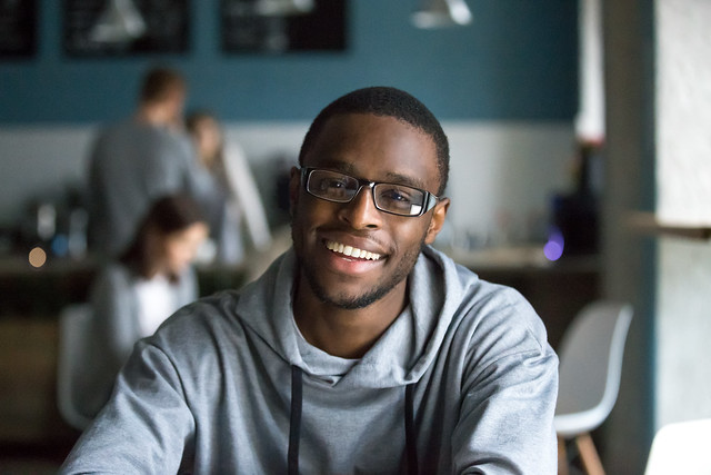 Portrait of smiling African American student looking at camera sitting in cafe