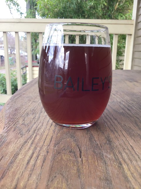 Asheville Dark Cherry Saison in glass on table outdoors.