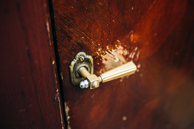 Close-up of a vintage door knob on a scratched wooden door