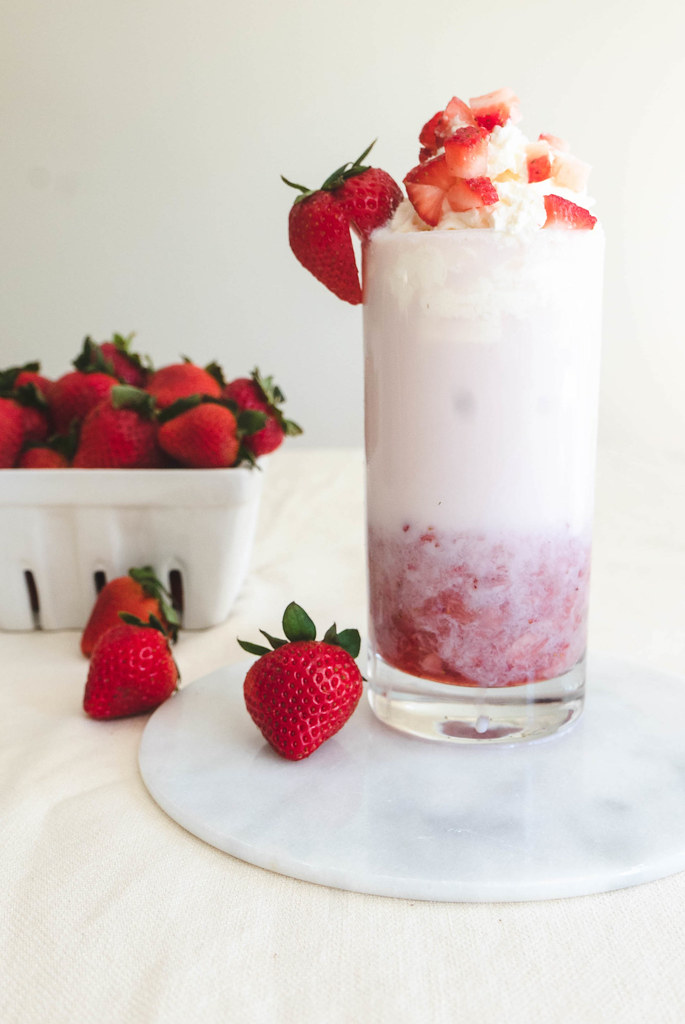 A side shot of Korean strawberry milk topped with homemade whipped cream. 
