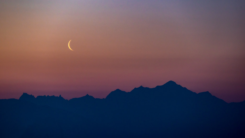 Une lune timide fait son apparition de bon matin au-dessus des Alpes.