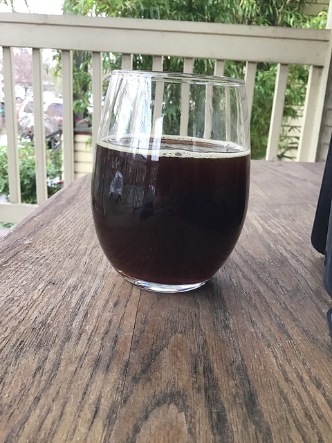 Gigantic's Massive barleywine ale, in glass on table outdoors. 