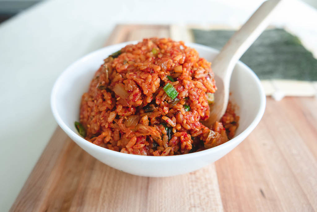 A bowl of kimchi fried rice on a cutting board. 