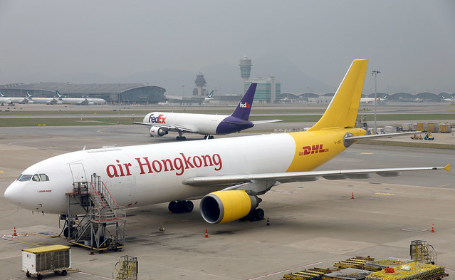 Fedex B767-300F N101FE departing HKG/VHHH, while AHK/DHL A300-605R B-LDE rests on a quiet cargo apron