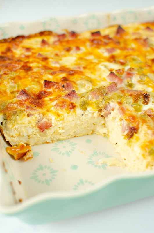 Ham, egg, and hashbrown casserole in a baking dish with 1 slice removed