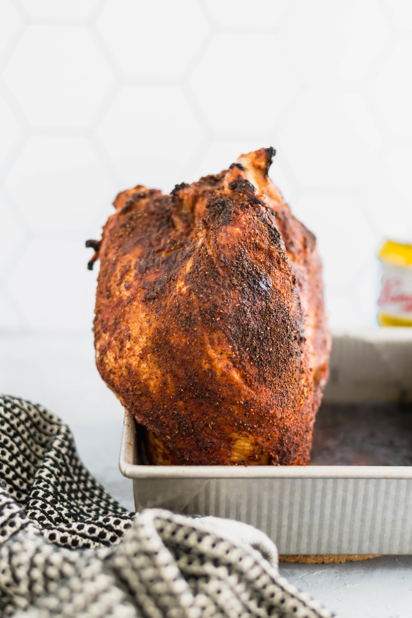 grilled beer can turkey leaning on a metal pan with a beer in the background.