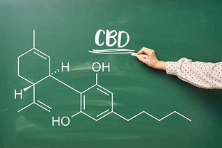 Hand of laboratory worker writing chemical formula of CBD on the chalkboard | by wuestenigel