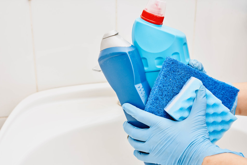 Housemaid holding bathroom cleaning supplies bottles