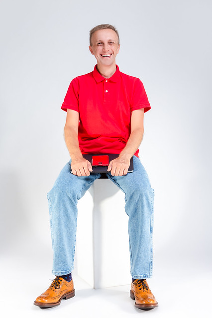 Distant Working Ideas. Portarit of Positive Caucasian Male in Red T-Shirt Posing With Laptop And Cellphone On White Background.