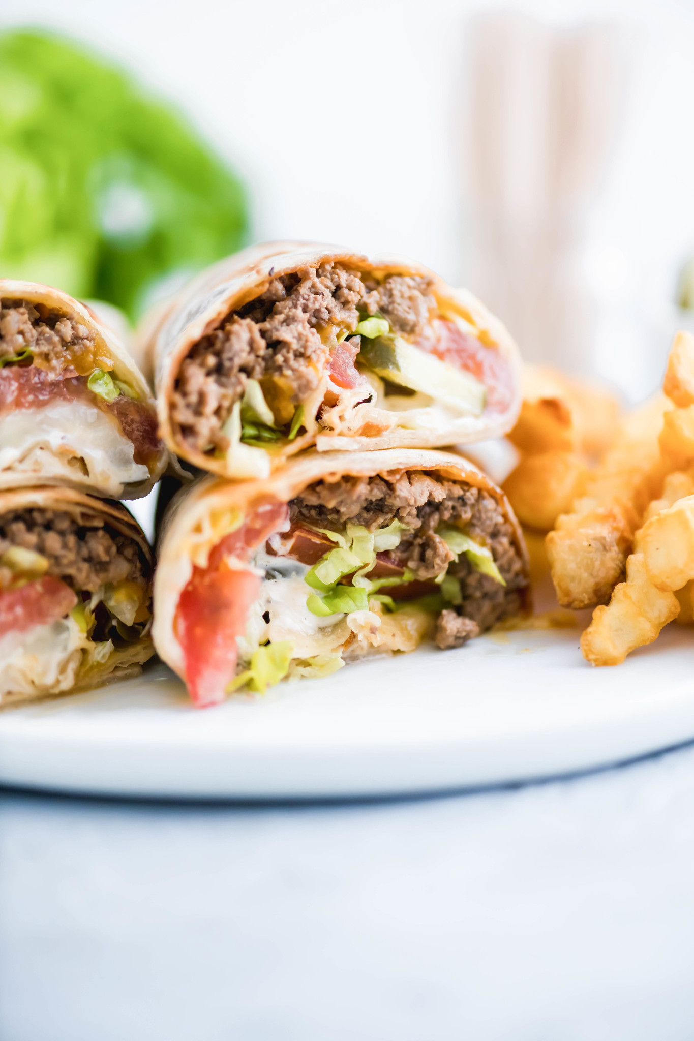 Two cheeseburger wraps cut in half and piled two on each to show interior of wrap.