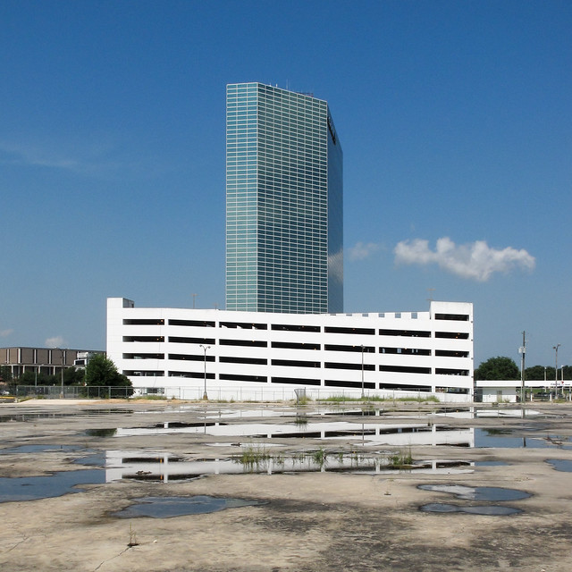 We are one parking garage reflected from multiple puddles in one expanse of concrete. We are one banktower from 1984.