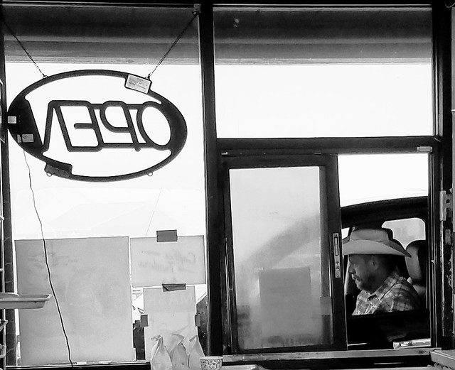 Man with a cowboy hat at a drive thru take-out window