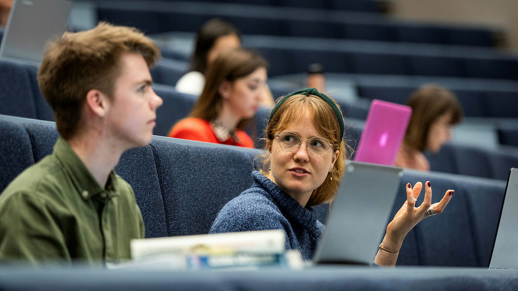 Two students chatting in a lecture theatre.