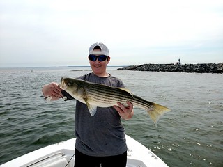 Photo of man in a boat holding a striped bass