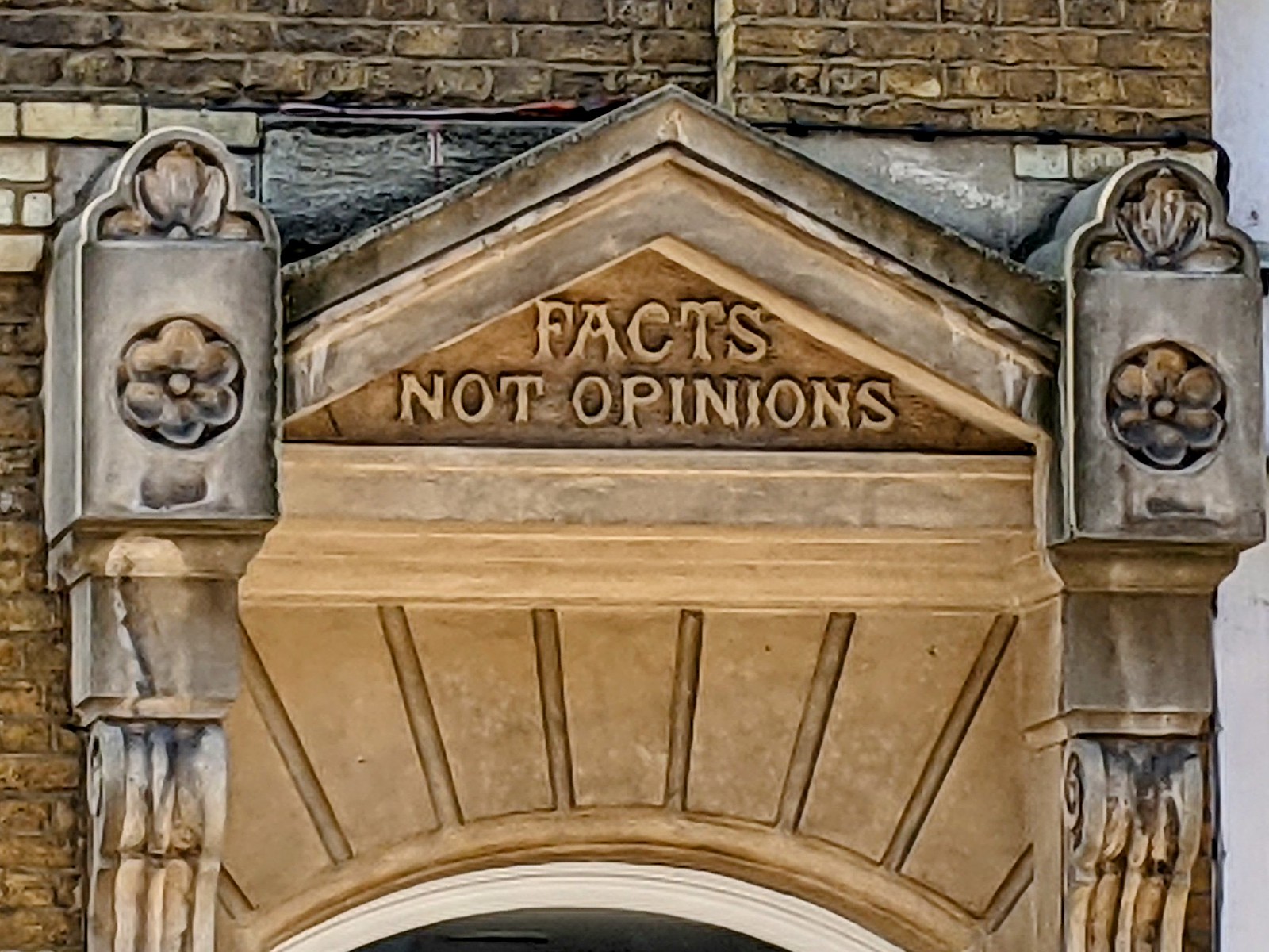 Facts Not Opinions slogan carved in stone above a door