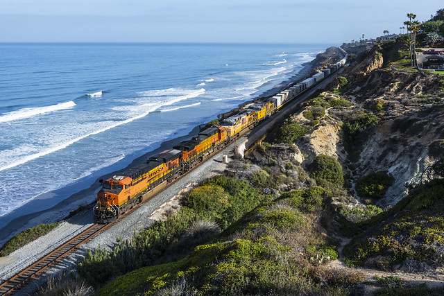 BNSF ES44DC 7792 leads a loaded military train alongside the Pacific Ocean in Del Mar, CA