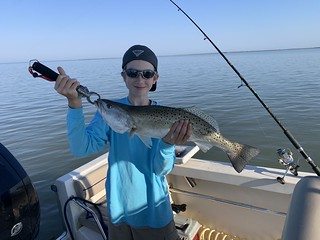 Photo of boy holding a speckled trout in a boat