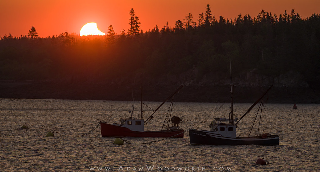 Partial Eclipse at Sunrise Over Fishing Boats