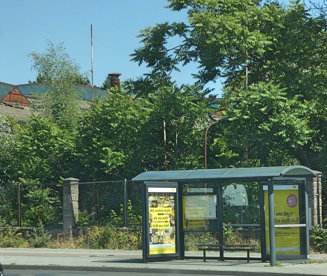 Bushaltestelle am Segelfliegerdamm, dahinter das Werksgelände mit Teilen der ehem. Henschel-Fabrikhalle