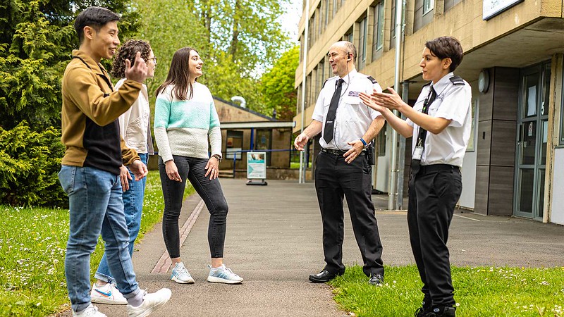Two of the University campus security team chat with three students on campus