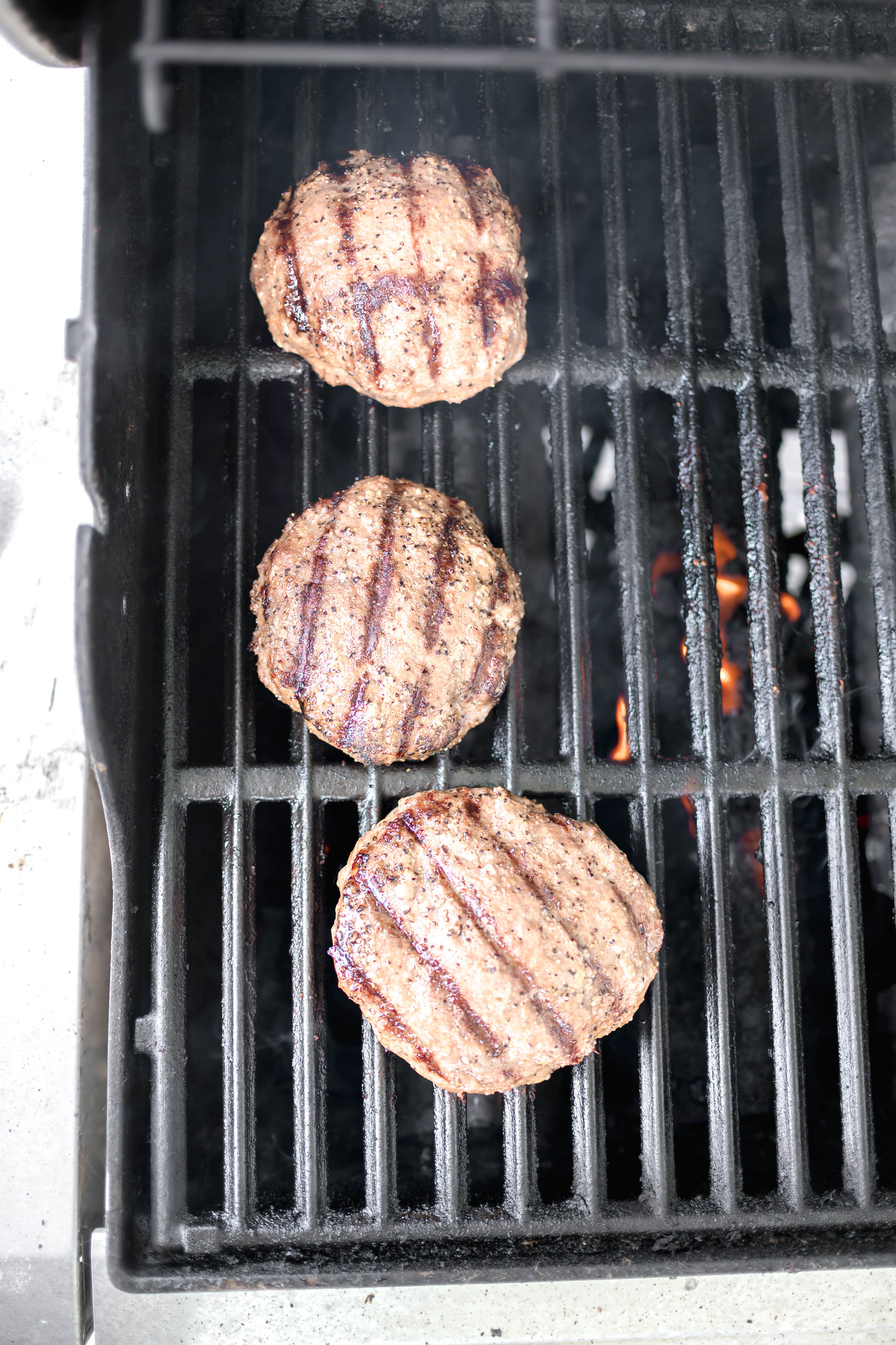 Cheddar stuffed turkey burgers cooking on the grill.