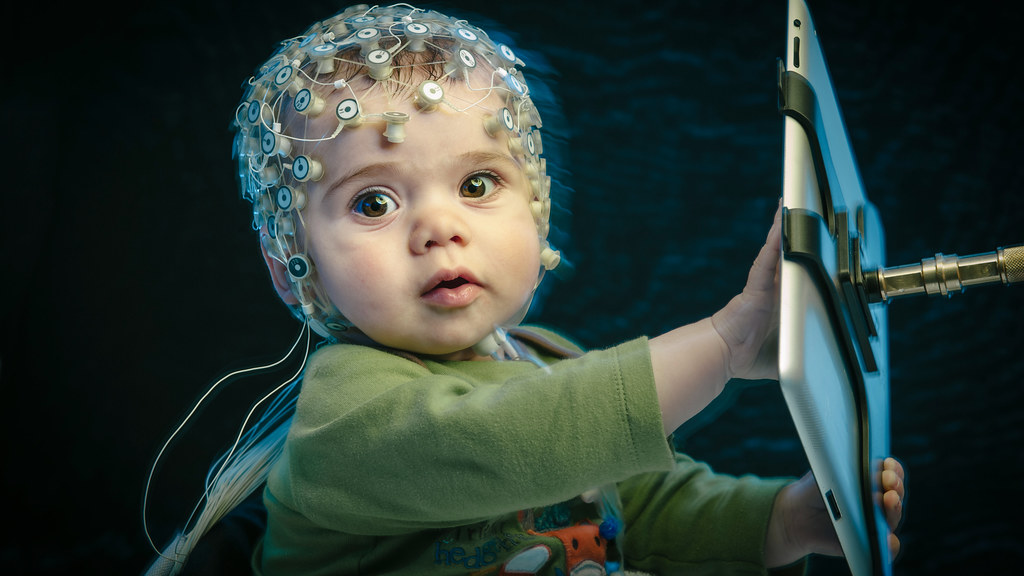 Infant wearing an EEG skullcap and using a tablet computer,