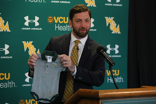 New AD Brian Mann holds up a W&M onesie he received for his 11-month-old son.