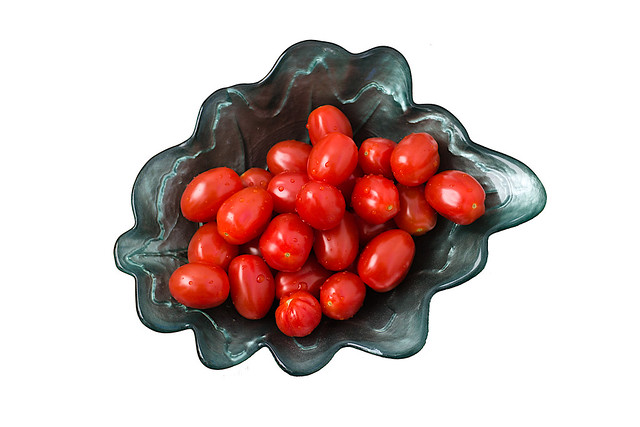 Small Roma tomatoes in a green bowl