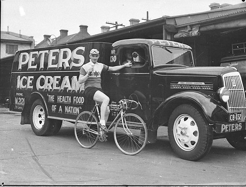 Cyclist Hubert Opperman poses next to an REO Speed Wagon truck advertising at Peters Ice Cream Factory, Redfern (taken for Bruce Small Ltd), Australia, 19 July 1938