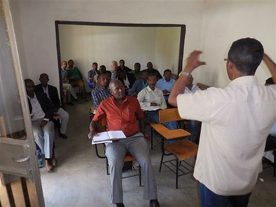 A man teaching at the front of a room of people.