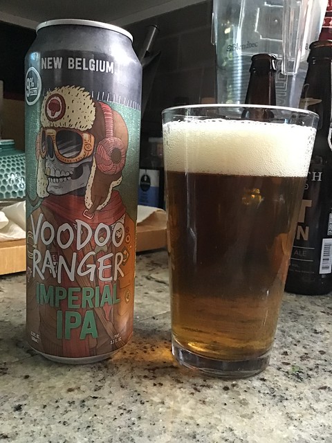Voodoo Ranger IPA by New Belgium in glass, next to can, on countertop