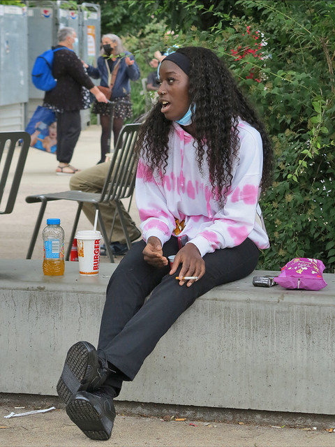 Pretty black girl smoking and drinking sitting in the Mandela Gardens