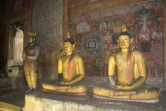 Sitting Buddha with saffron robes - Murals in the background