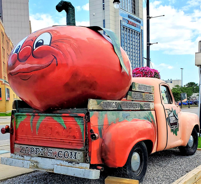 Vintage peach Studebaker truck with anthropomorphic cartoon smiling giant tomato