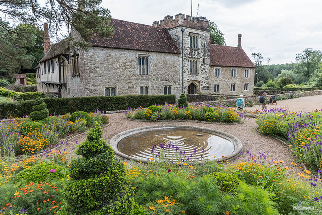 Newer stone-built section of Ightham Mote, Ightham, Kent, England from one of several formal garden areas with round water-feature.