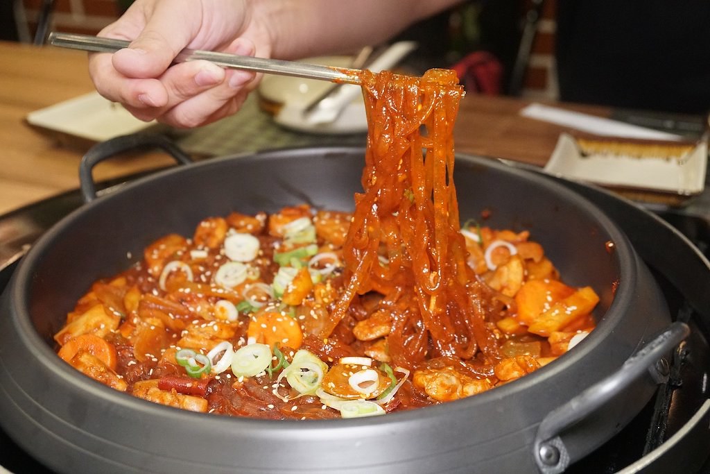 A photo of noodles being held by Korean chopsticks.
