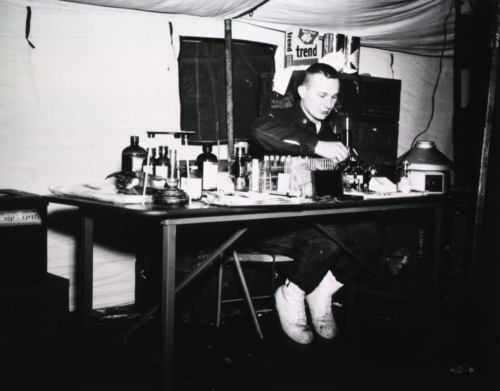 Pfc Hackley, lab technician, 60th Field Hospital, prepares to examine a blood slide under the microscope as part of a diagnonis