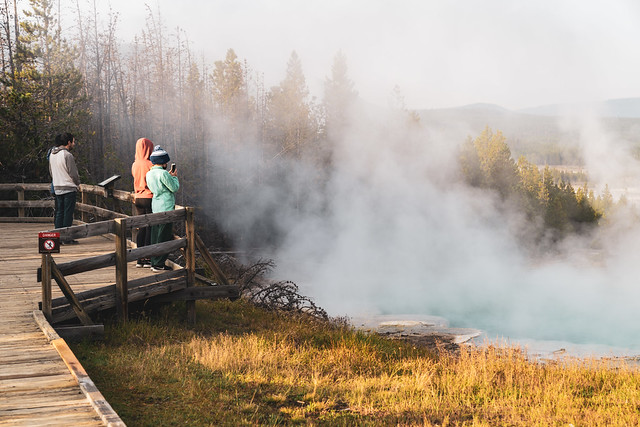 Wyoming, USA - August 25, 2021: Tourists take photos of a hot spring with steam in Norris Geyser Basin area